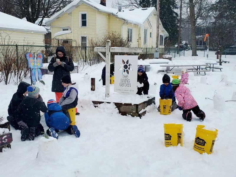 Group of students with teacher tending to a snowy garden.
