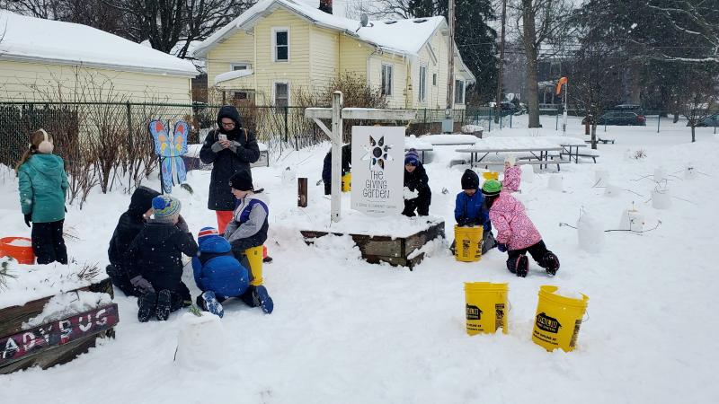 Group of students with teacher tending to a snowy garden.