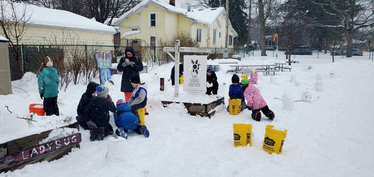 Group of students with teacher tending to a snowy garden.