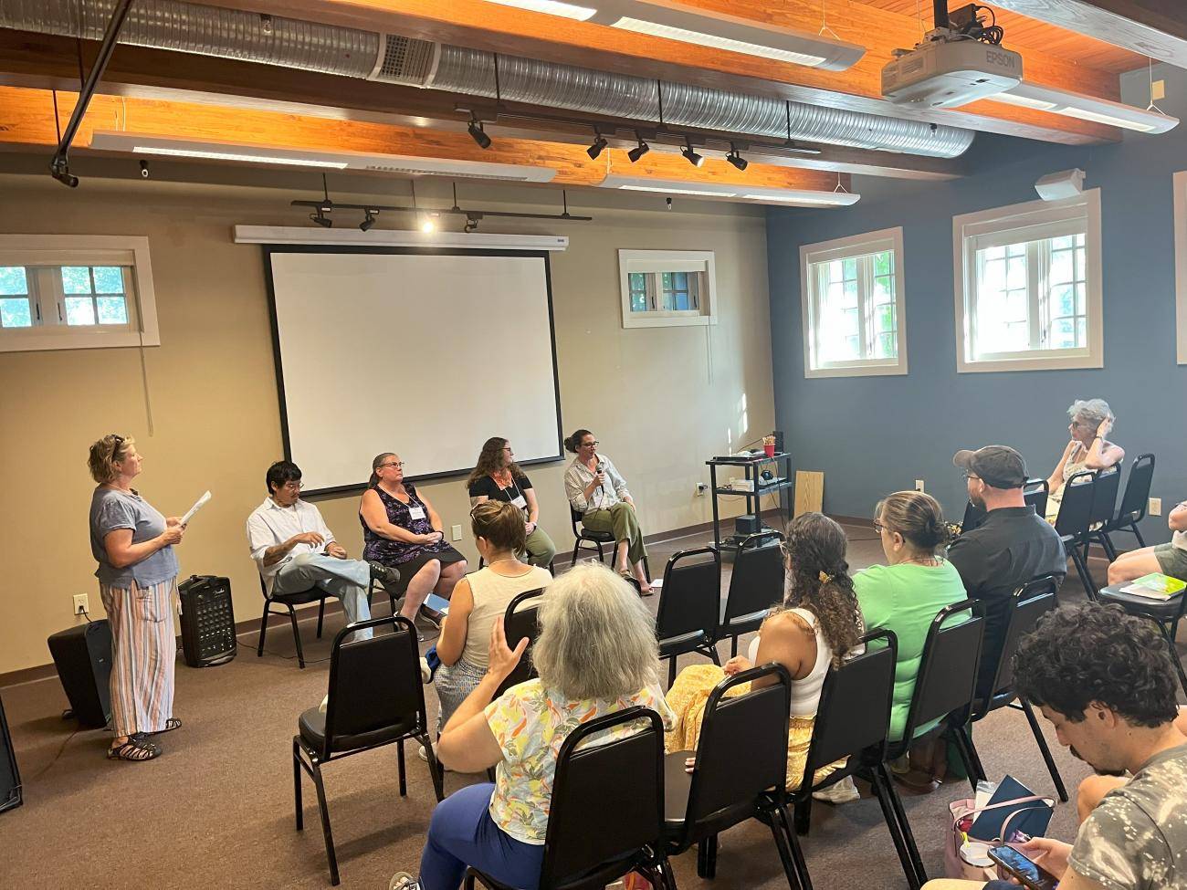 Four panelist plus a moderator at the front of the room full of an audience.